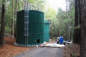 Two large, green water storage tanks at a California camp