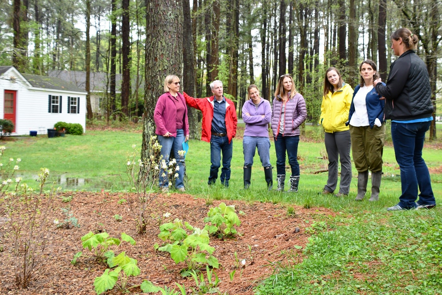 Landowner Assistance Coordinator Nicole Barth (far right) explains some of the features of Janet’s (far left) rain garden to visitors. Plants were beginning to emerge on the early spring day.