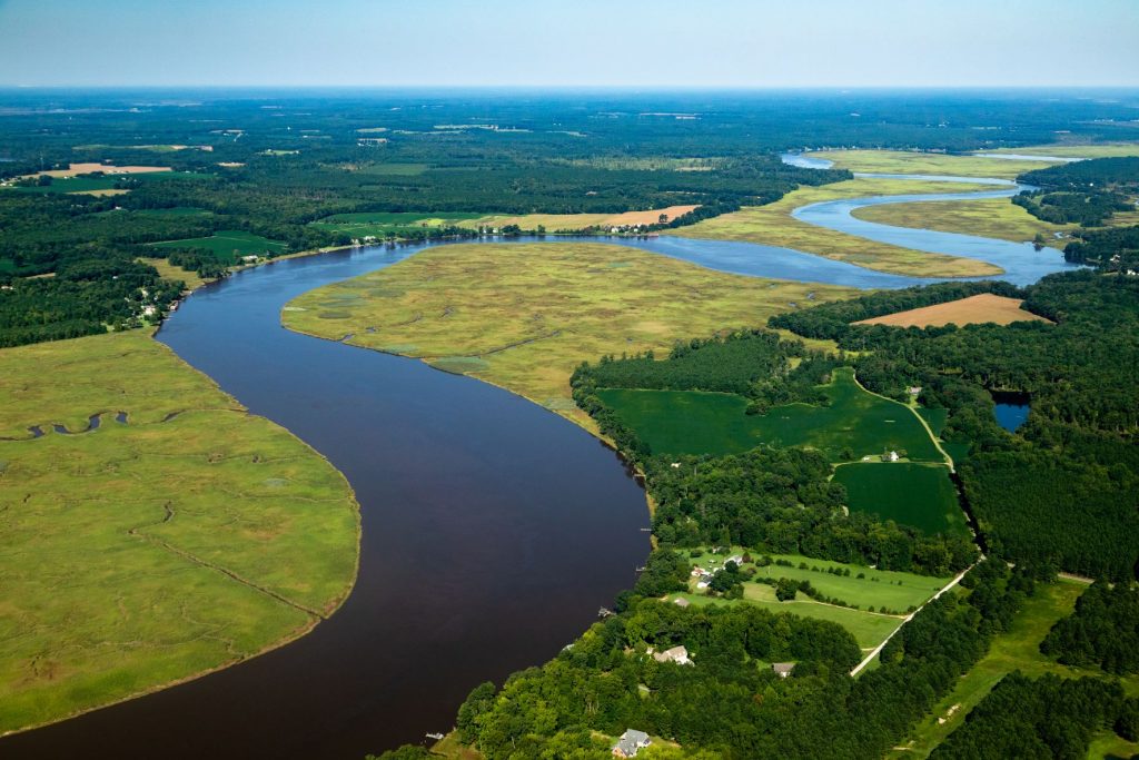 A river running through a low-lying patchwork landscape of farms, forests, and marshes. Credit: Chesapeake Bay Program