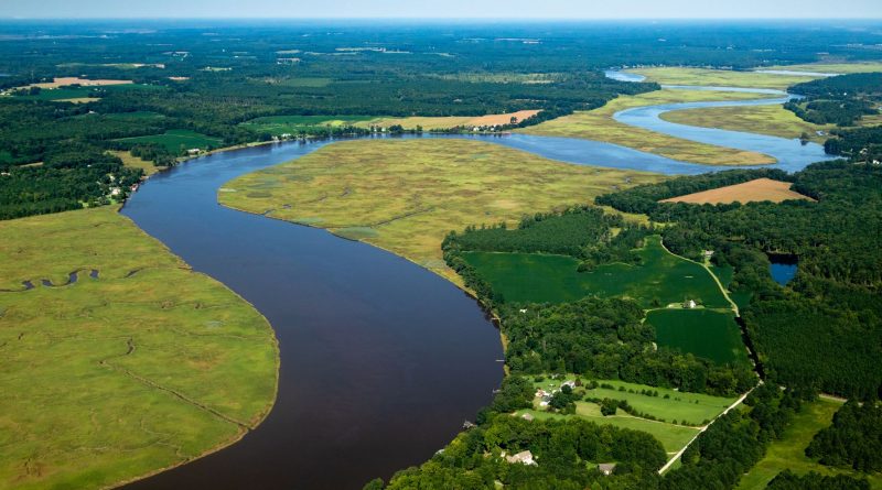 A river running through a low-lying patchwork landscape of farms, forests, and marshes. Credit: Chesapeake Bay Program